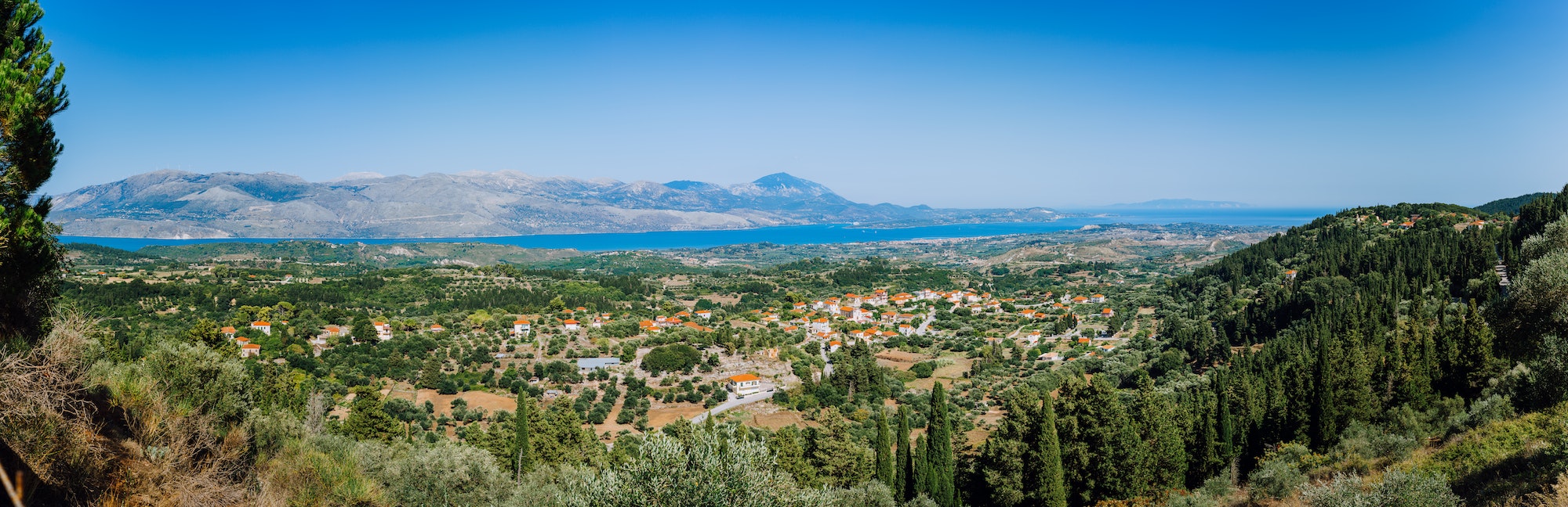 Ultra wide panormaic view of idyllic valley town with red roofs on mediterranean island. Olive